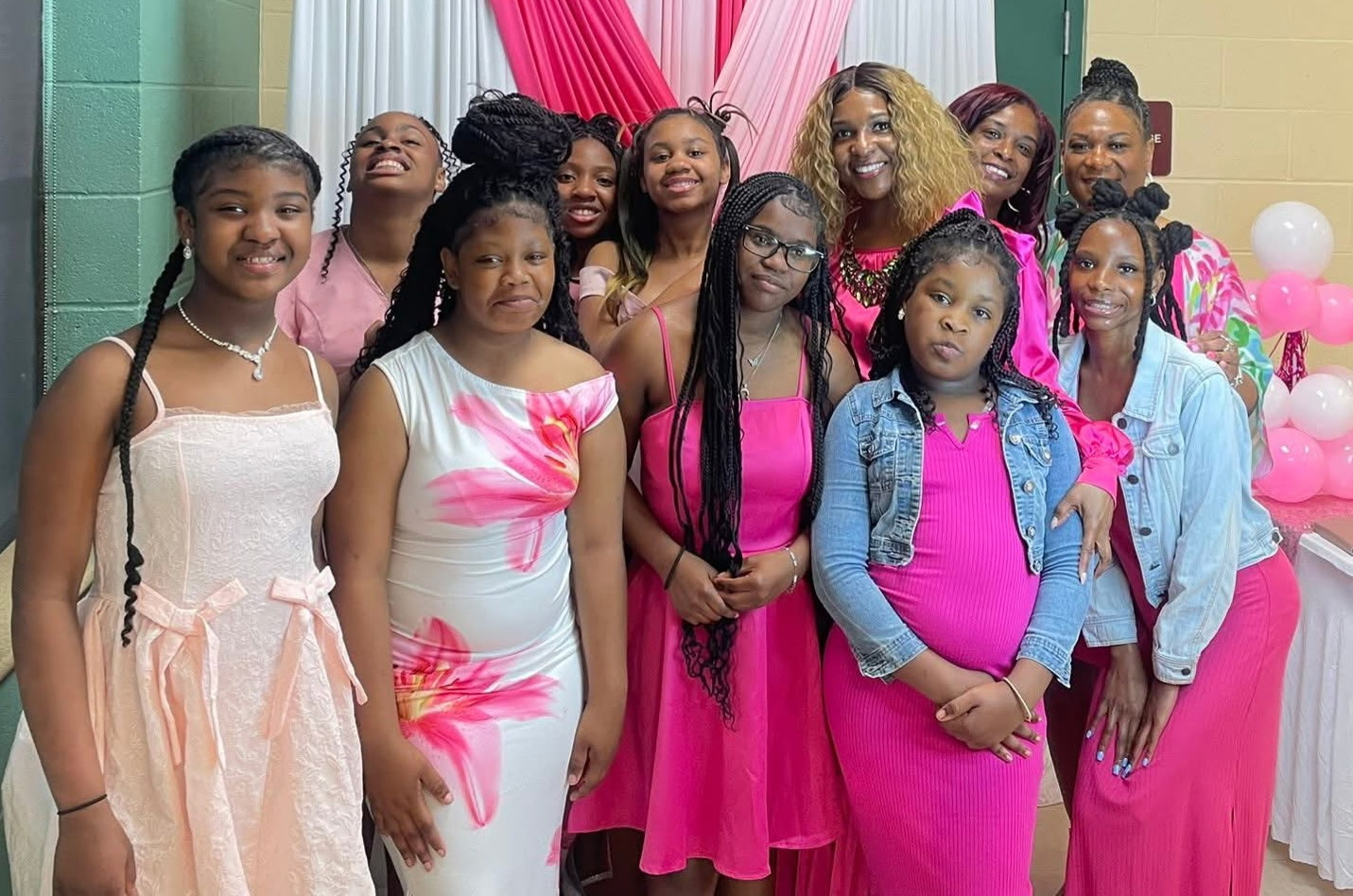 21 Shades of Pink Empowerment cohort with founder Tiffany Owens, smiling and holding pink gift bags in front of the program backdrop